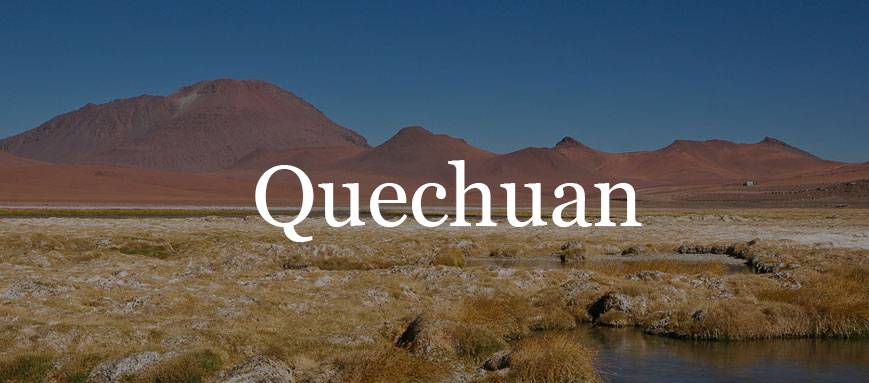 A grassland with large red mountains in the background, overlaid with Quechuan text