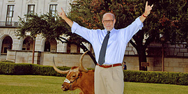 Prof. Howard Miller gives the Hook-Em Horns sign with Bevo