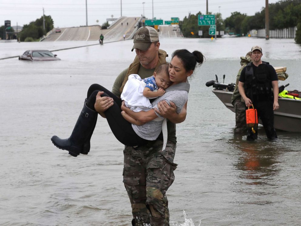 Houston Police SWAT officer Daryl Hudeck carries carries civilians from their home , Aug. 27, 2017, in Houston.