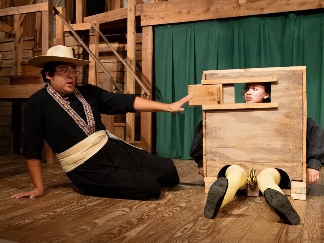 two performers clutching each other, one pointing and looking concerned