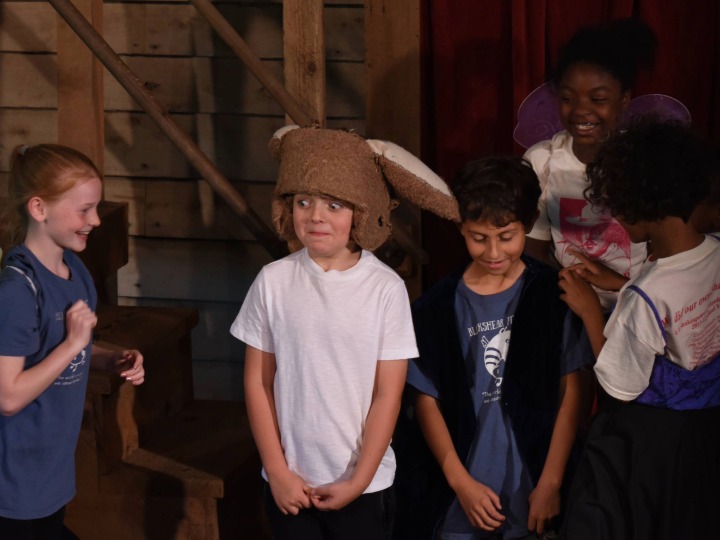 image of a performer wearing donkey's ears surrounded by other young performers laughing