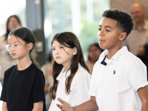 image of three young performers, one gestures to the audience